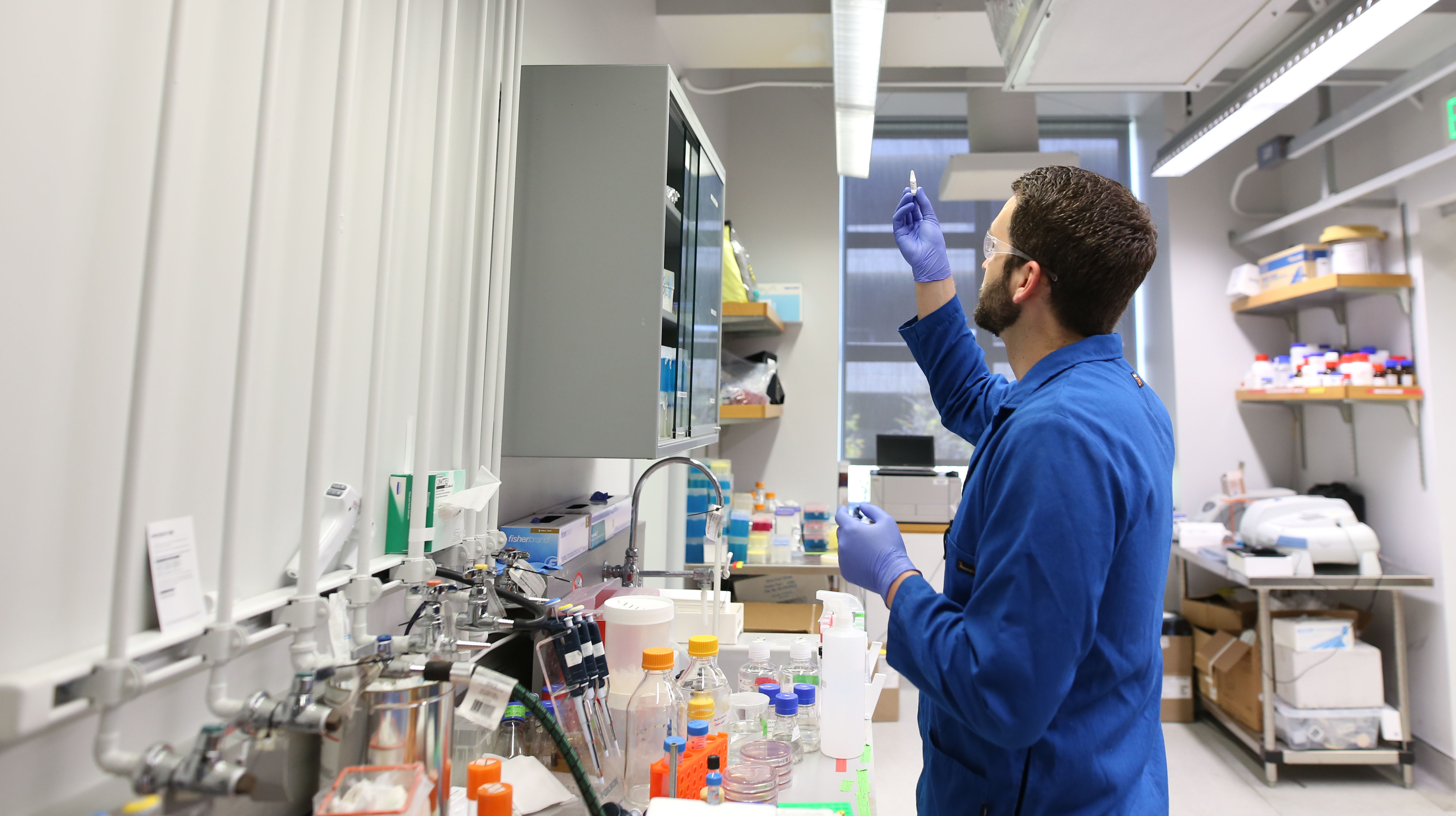 A man in lab coat looking at test tube in a laboratory.