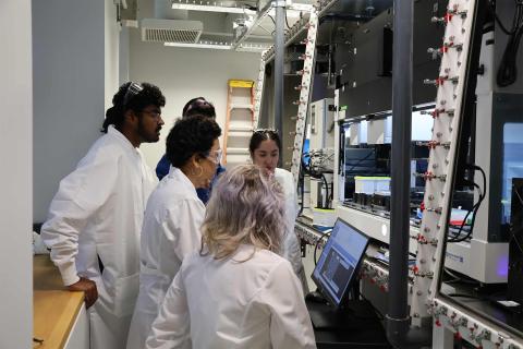 People in lab coats gathered around a computer.